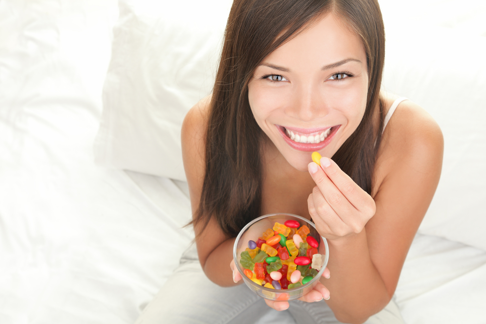 young woman eating candy in bed